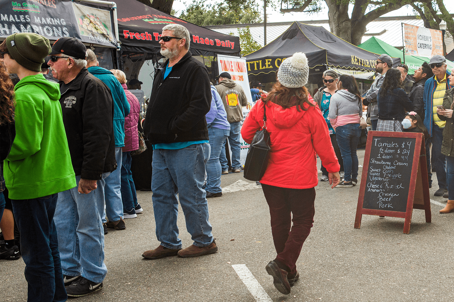 Image of people visiting different vendors with popup tents at the Tamale Festival.